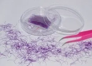 A purple thread and pink scissors on top of a table.