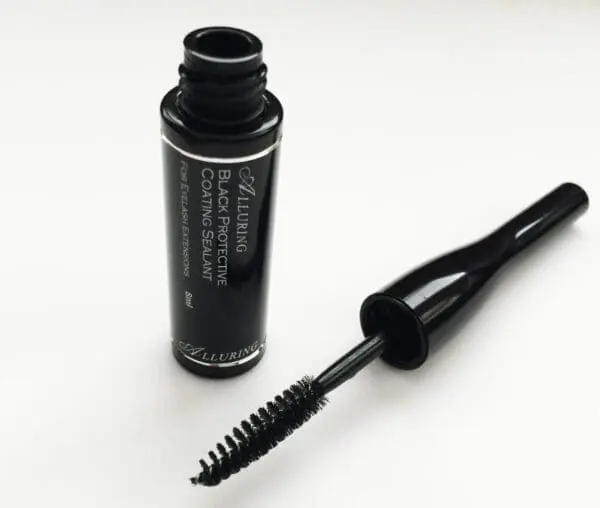 A bottle of mascara next to a brush.