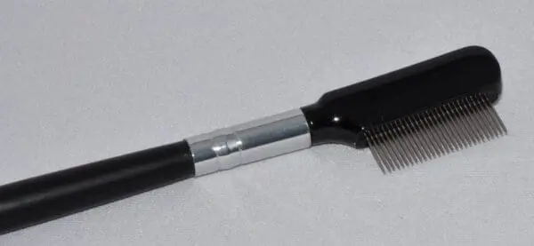 A comb with a metal handle on top of it.