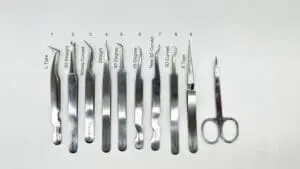 A white table with many pairs of scissors and some types