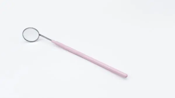 A pink toothbrush with a metal handle on top of it.
