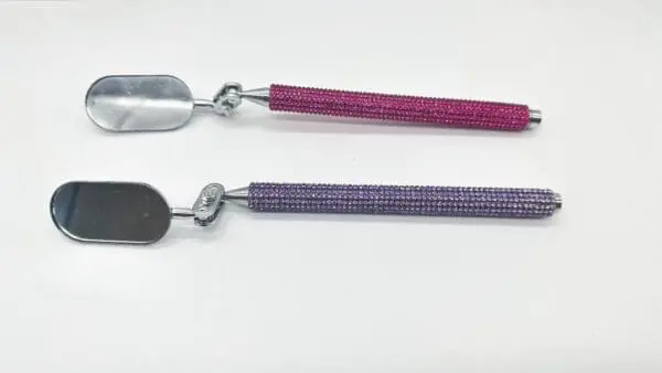 Two spoons with a purple handle and one pink handle.