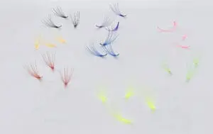A group of different colored eyelashes on top of white paper.