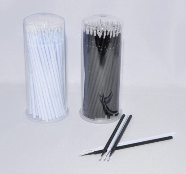 A pair of black and white toothbrushes in plastic tubes.