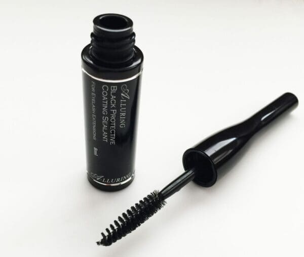 A bottle of black mascara next to a brush.