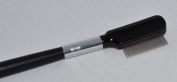 A comb with a metal handle on top of it.