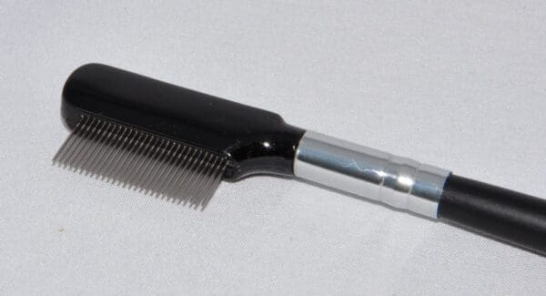 A comb with a metal handle on top of it.