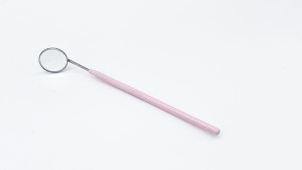 A pink toothbrush with a metal handle on top of it.