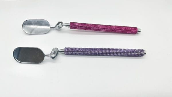 Two spoons with a purple handle and one pink handle.